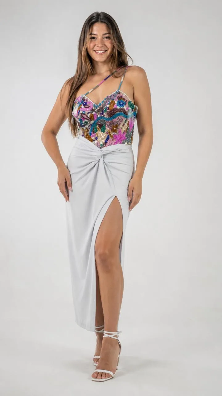 Foto gerada com fundo claro de estúdio: modelo com top bordado colorido e saia branca